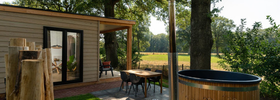 Zona exterior de una tiny house con fachada de madera, sauna y jacuzzi en Holiday Park Mölke, Países Bajos.