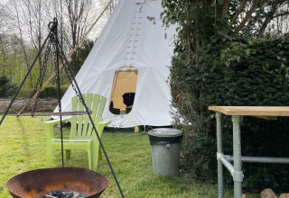 Tipitent bij Buytenplaets Abelen in Flevoland met vuurkorf, stoelen en buitentafel in het gras.