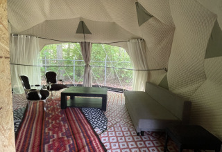 Interieur van een koepeltent met stoelen, tafel en sofa bij Buytenplaets Abelen in Flevoland, Nederland.