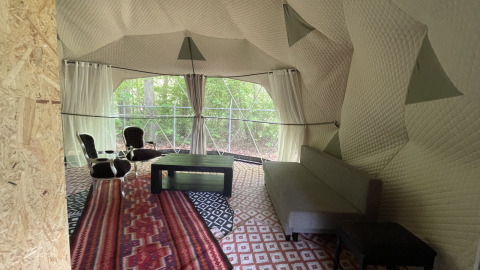 Vista interior de una cabaña domo con asientos, mesa y sofá en Buytenplaets Abelen en Flevoland, Países Bajos.