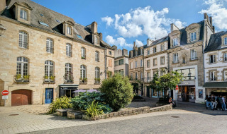 Charmanter Platz mit historischen Gebäuden nahe Quimper in der Bretagne, Frankreich, an einem sonnigen Tag.