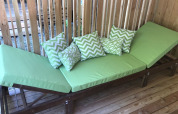 Sillón verde con cojines estampados en terraza de madera del SunLodge Catalpa, fondo de listones de madera.