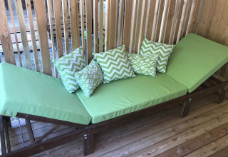 Sillón verde con cojines estampados en terraza de madera del SunLodge Catalpa, fondo de listones de madera.