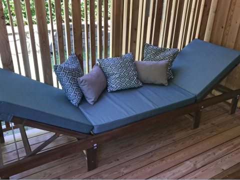 Sillón exterior con cojines azules y marco de madera en SunLodge Catalpa, rodeado de paneles de madera.