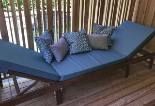Sillón exterior con cojines azules y marco de madera en SunLodge Catalpa, rodeado de paneles de madera.