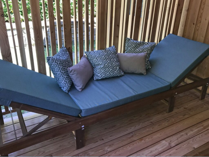Outdoor lounger with blue cushions and wooden frame at SunLodge Catalpa, surrounded by wooden slats.