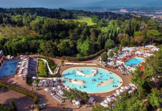 Vista aérea de un lodge con varias piscinas, tumbonas y vegetación exuberante en un entorno de colinas.