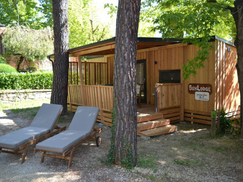 SunLodge BigLeaf en hu Norcenni Girasole Village, Italia, rodeado de árboles y con dos tumbonas enfrente.
