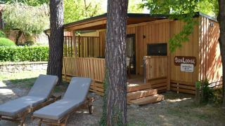 SunLodge BigLeaf in hu Norcenni Girasole Village, Italië, met bomen rondom en twee ligzetels vooraan.