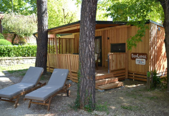 SunLodge BigLeaf in hu Norcenni Girasole Village, Italië, met bomen rondom en twee ligzetels vooraan.