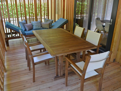Terraza exterior con mesa, sillas y tumbona en SunLodge BigLeaf de hu Norcenni Girasole Village en Italia.