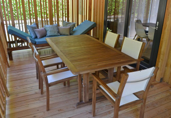 Terras met houten tafel, stoelen en ligstoel bij SunLodge BigLeaf, hu Norcenni Girasole Village in Italië.