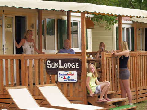Gezin op het houten terras van SunLodge Maple bij hu Norcenni Girasole Village in Italië geniet samen.