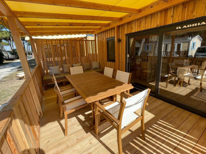 Terraza exterior de madera en SunLodge Babul con mesa, sillas y zona de estar cubierta por toldo.