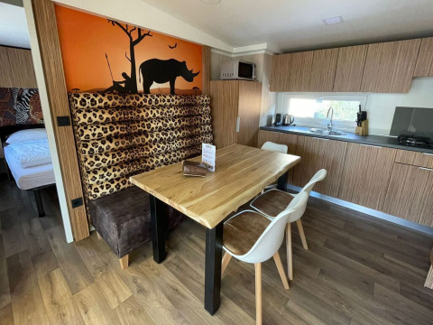 Dining area and kitchen in SunLodge Babul, with wooden table, leopard booth seating, and rhino mural.
