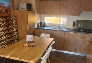 Cucina moderna alla SunLodge Babul con mobili in legno, tavolo da pranzo e cuscini leopardati.
