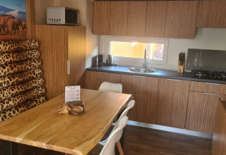 Moderne køkken i SunLodge Babul med trædetaljer, spisebord, leopardmønstrede hynder og vindue.