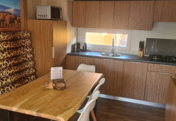 Cocina moderna en SunLodge Babul con armarios de madera, mesa de comedor y cojines de leopardo.