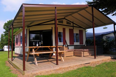 Tienda safari Tentlodge en Camping Vinkenhof, Países Bajos, con terraza, mesa de pícnic y asientos.