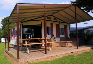 Safari-Zelt Tentlodge auf Camping Vinkenhof in den Niederlanden mit Veranda, Sitzbank und Loungemöbeln.