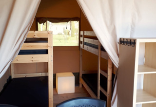 Interieur van een safaritent op Camping Oos Heem in België met stapelbedden, stoelen en kast.