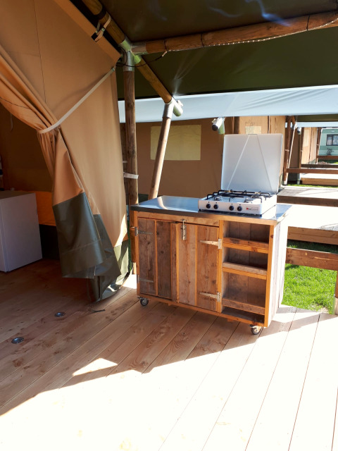 Buitenkeuken met gasfornuis in een safaritent op Camping Oos Heem in België, houten kast en planken.