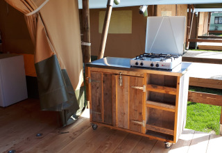 Udendørs køkken med gaskomfur i en safaritelt på Camping Oos Heem i Belgien, træbord og hylder.