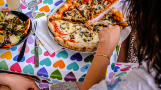 Dos personas disfrutan de pizza y ensalada en una mesa colorida en Medrose Camping en Auvergne-Rhône-Alpes, Francia.