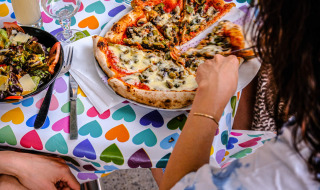 Dos personas disfrutan de pizza y ensalada en una mesa colorida en Medrose Camping en Auvergne-Rhône-Alpes, Francia.