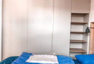 Dormitorio de la Forest lodge en Vakantiepark De Luttenberg, Países Bajos, con ropa de cama azul y estantes.