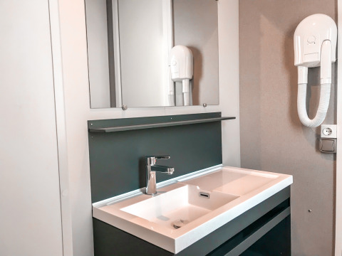 Moderno lavabo de baño con espejo y secador de pelo en Forest Lodge del Vakantiepark De Luttenberg, Países Bajos.