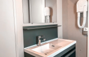 Modernes Badezimmer mit Waschbecken, Spiegel und Haartrockner in der Forest Lodge im Vakantiepark De Luttenberg.
