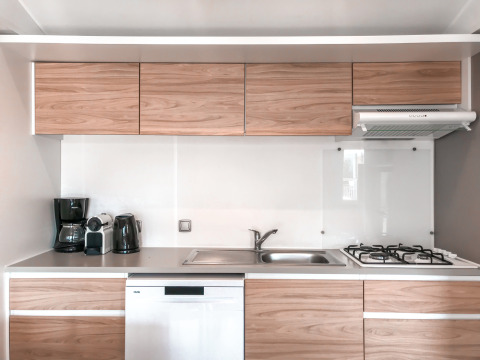 Moderne keuken in Forest Lodge bij Vakantiepark De Luttenberg, Nederland, met houten kasten en toestellen.