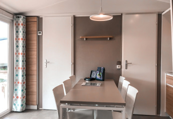 Spisebord med hvide stole i Forest Lodge på Vakantiepark De Luttenberg, Holland, moderne interiør.