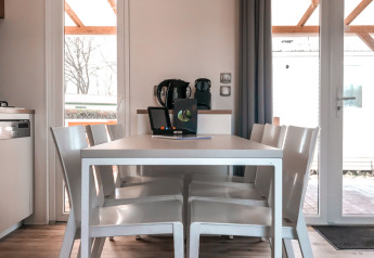 Moderne spisestue i Forest lodge ved Vakantiepark De Luttenberg med hvidt bord, stole og lysindfald.