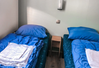 Dos camas individuales con ropa de cama azul en Forest Lodge, Vakantiepark De Luttenberg, Países Bajos.