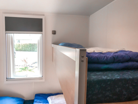 Literas junto a una ventana en una habitación Forest lodge de Vakantiepark De Luttenberg, Países Bajos, luminosa.