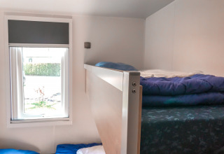 Literas junto a una ventana en una habitación Forest lodge de Vakantiepark De Luttenberg, Países Bajos, luminosa.
