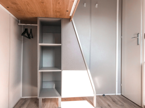 Moderne kast met open rekken en hangers in het Forest Lodge van Vakantiepark De Luttenberg, Nederland.