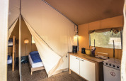 Indvendigt billede af en safari-telt lodge på Vakantiepark De Luttenberg med soveområde og tekøkken.