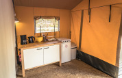 Indvendig billede af et Safari-teltkøkken med komfur, kaffemaskine og vask på Vakantiepark De Luttenberg.