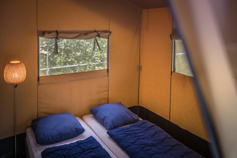 Vista interior de tienda Safari en Vakantiepark De Luttenberg, Países Bajos, con dos camas y ropa de cama azul.