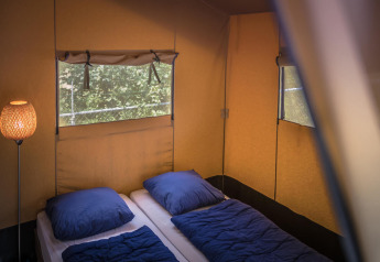 Indvendig udsigt af Safari-telt på Vakantiepark De Luttenberg i Holland med to senge og blå sengetøj.