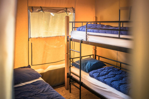 Vista interior de la tienda Safari con literas y ropa de cama en Vakantiepark De Luttenberg, Países Bajos.
