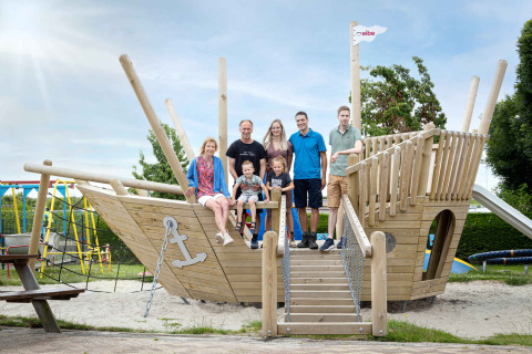 Familia posando en un gran barco de juegos de madera en Camping Waddenzee en el Norte de Holanda, Países Bajos.