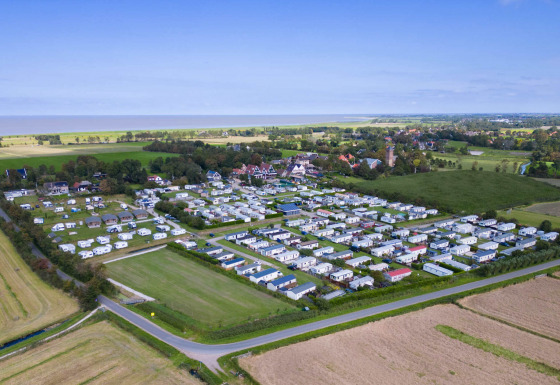 Luftfoto af Camping Waddenzee feriepark med campingvogne og grønne marker i Nordholland, Holland.