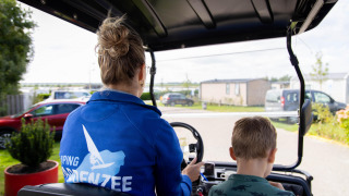 Una mujer y un niño pasean en carrito de golf por Camping Waddenzee, un parque vacacional en Holanda Septentrional.