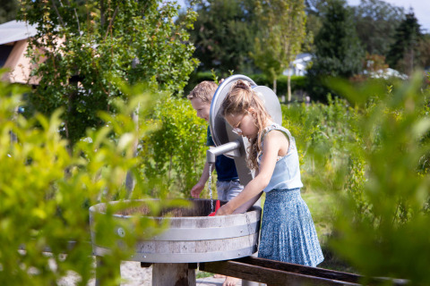 Dos niños juegan en una zona de juegos de agua al aire libre en Camping Waddenzee, Holanda Septentrional.