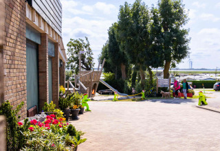 Holiday scene at Camping Waddenzee in North Holland, Netherlands with playground, flowers, and families.