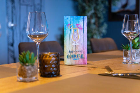 Mesa con menú de cócteles en Camping Waddenzee, Holanda Septentrional, Países Bajos, con copas y decoración.